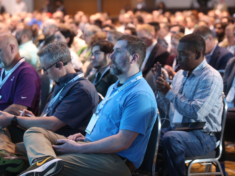 A seated crowd listens to a talk. Decorative Image.