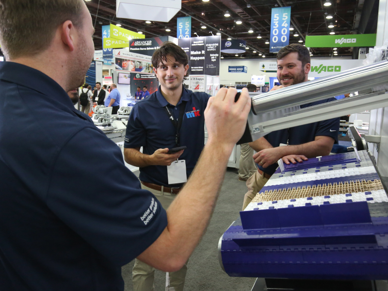 Three men talk on the Automate show floor.